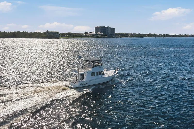  Yacht Photos Pics 1998 Mainship 350 Trawler cruising on a sunny, sparkling waterway.