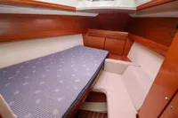 Cozy cabin interior of 2007 Dufour 40 Performance yacht with wooden finish and comfortable bedding.