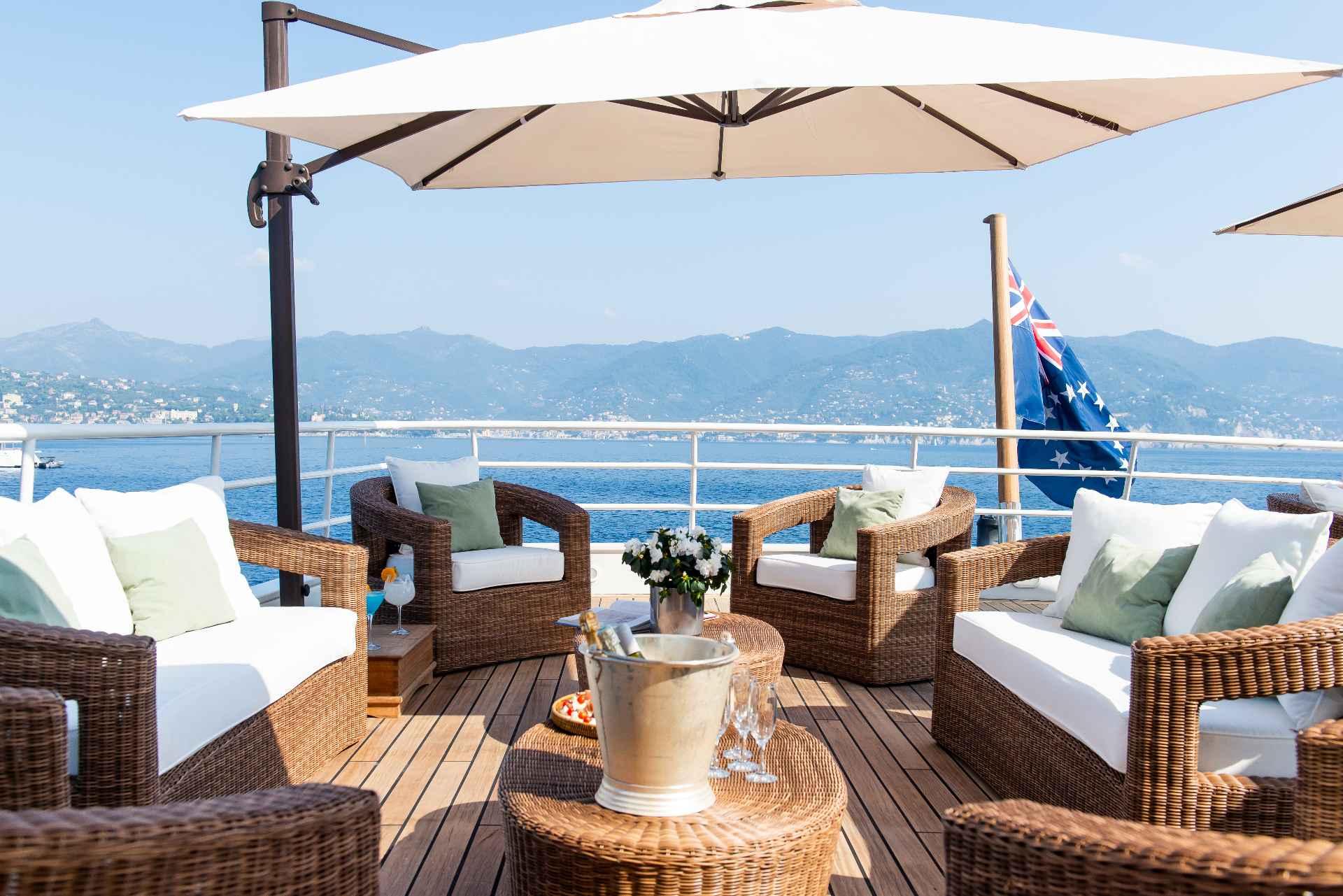 Luxurious yacht deck with wicker furniture, umbrellas, and ocean view, Custom Conversion 1980.