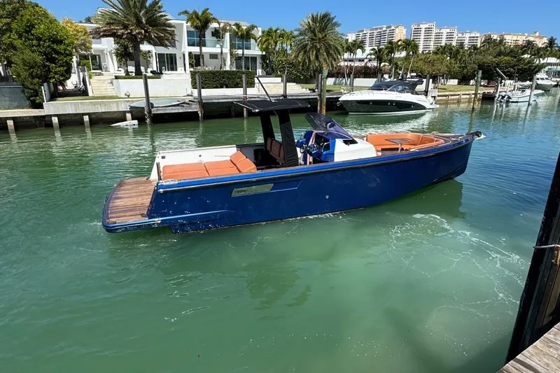  Yacht Photos Pics 2017 Fjord 36' Open boat in marina, blue hull, modern waterfront homes in background.