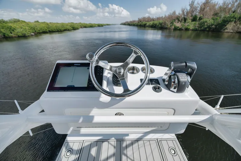  Yacht Photos Pics 2022 Freeman 47 boat helm with steering wheel and navigation system on a calm river.