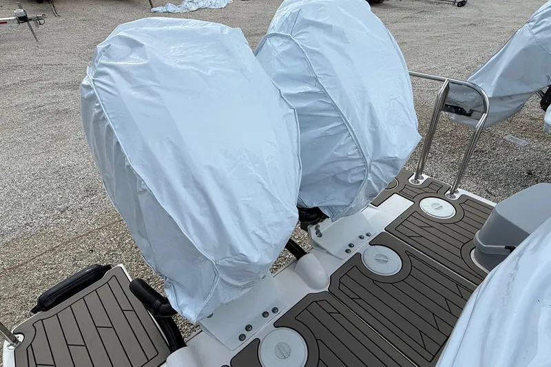  Yacht Photos Pics Covered outboard motors on a 2025 Cutwater C-32 CB boat, resting on a gravel surface.