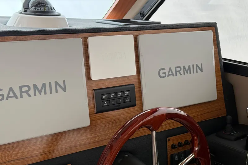  Yacht Photos Pics 2025 Cutwater C-32 CB dashboard featuring Garmin navigation displays and a wooden steering wheel.