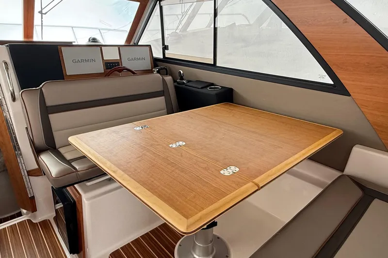  Yacht Photos Pics 2025 Cutwater C-32 CB interior with wooden table, cushioned seating, and Garmin navigation displays.