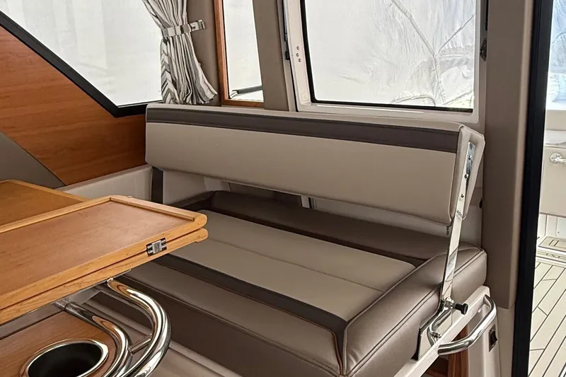  Yacht Photos Pics Interior of 2025 Cutwater C-32 CB boat with cushioned seating and wooden table.