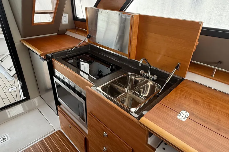  Yacht Photos Pics 2025 Cutwater C-32 CB yacht kitchen with stove, sink, and wooden cabinetry.