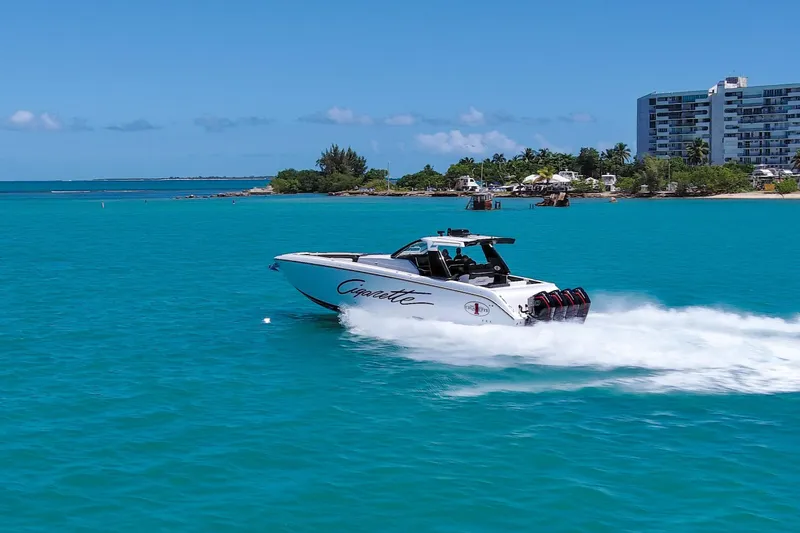  Yacht Photos Pics 2025 Cigarette 42 Auroris speedboat cruising on turquoise waters near a coastal city.