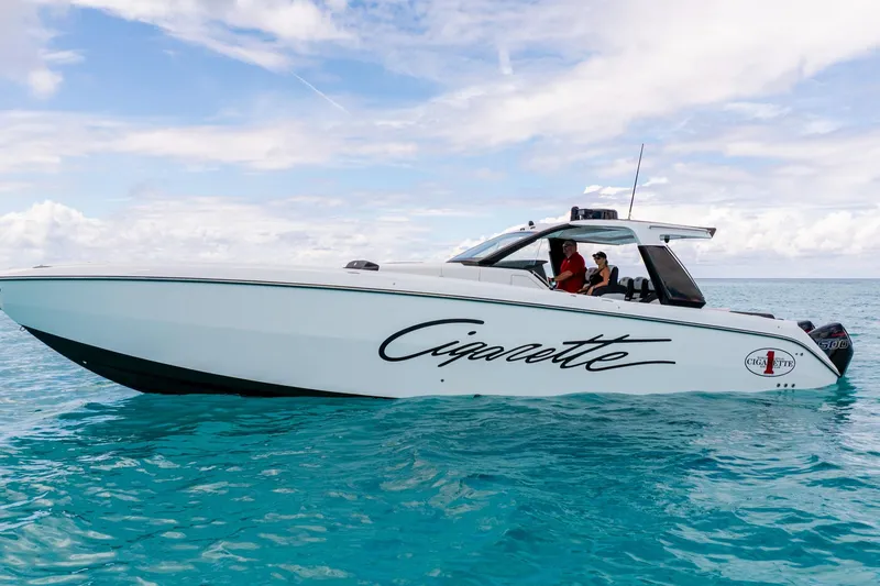  Yacht Photos Pics 2025 Cigarette 42 Auroris boat cruising on clear blue water under a partly cloudy sky.
