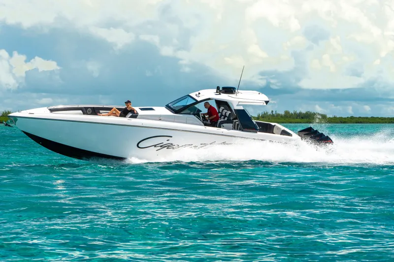  Yacht Photos Pics 2025 Cigarette 42 Auroris speedboat cruising on turquoise water under a cloudy sky.