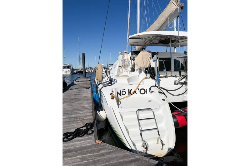 No Ka Oi Yacht Photos Pics 2005 Lagoon 380 S2 catamaran docked at marina under clear blue sky.
