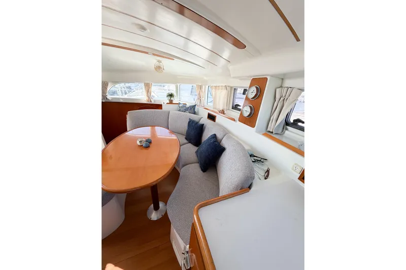 No Ka Oi Yacht Photos Pics Interior of 2005 Lagoon 380 S2 yacht with cozy seating and elegant wooden table.