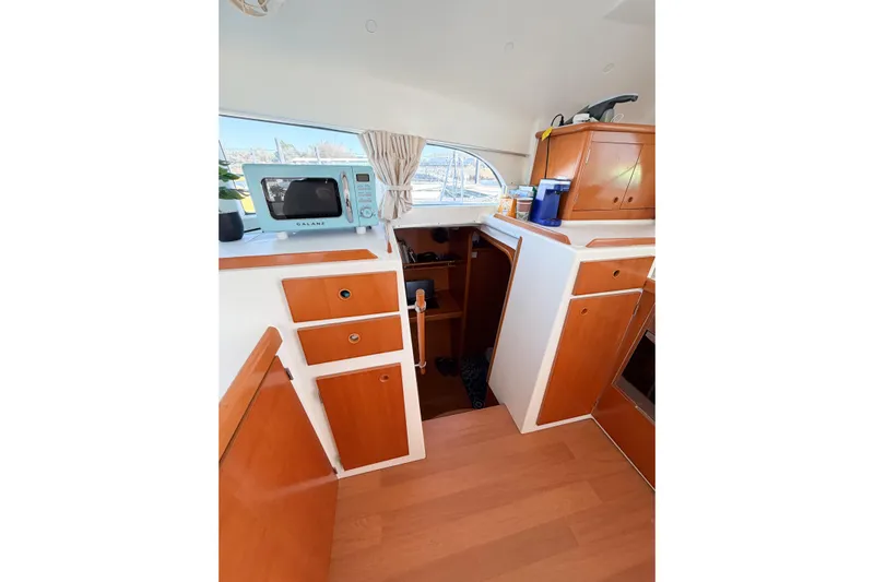 No Ka Oi Yacht Photos Pics Interior of 2005 Lagoon 380 S2 yacht kitchen with microwave and wooden cabinets.