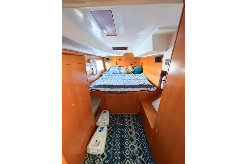 No Ka Oi Yacht Photos Pics Cozy cabin interior of 2005 Lagoon 380 S2 catamaran with bed and wooden furnishings.