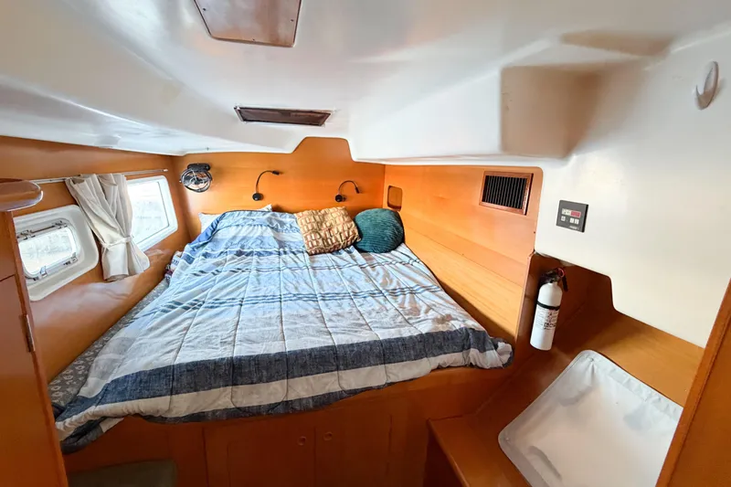 No Ka Oi Yacht Photos Pics Cozy cabin interior of 2005 Lagoon 380 S2 catamaran with bed, porthole, and fire extinguisher.
