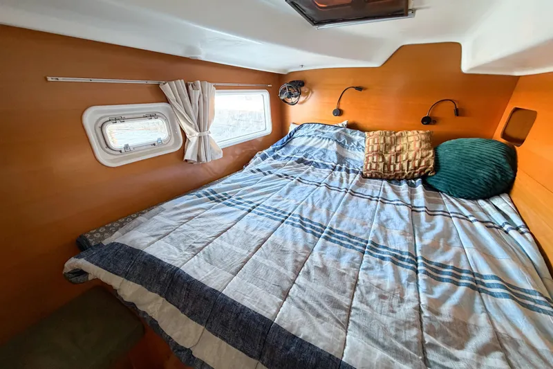 No Ka Oi Yacht Photos Pics Cozy cabin interior of 2005 Lagoon 380 S2 catamaran with bed and porthole.