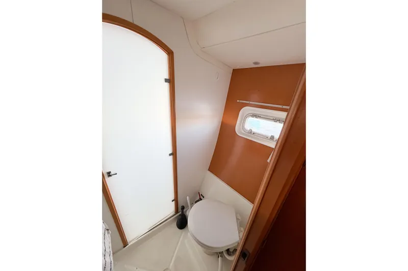 No Ka Oi Yacht Photos Pics Bathroom interior of 2005 Lagoon 380 S2 catamaran with window and white door.