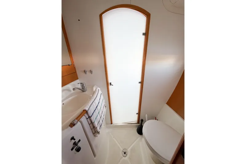 No Ka Oi Yacht Photos Pics Compact bathroom in 2005 Lagoon 380 S2 yacht, featuring sink, toilet, and frosted door.