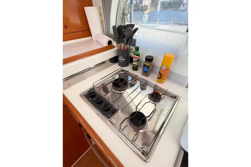 No Ka Oi Yacht Photos Pics Compact kitchen area in a 2005 Lagoon 380 S2 yacht with stove and cooking essentials.