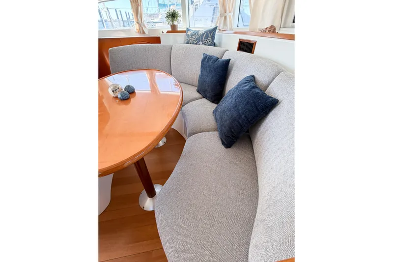 No Ka Oi Yacht Photos Pics Interior of 2005 Lagoon 380 S2 yacht with curved seating and wooden table.