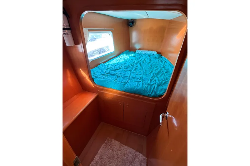 No Ka Oi Yacht Photos Pics Cozy cabin interior of 2005 Lagoon 380 S2 catamaran with blue bedding and wooden finish.