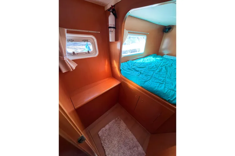 No Ka Oi Yacht Photos Pics Interior cabin of 2005 Lagoon 380 S2 catamaran with bed and porthole windows.
