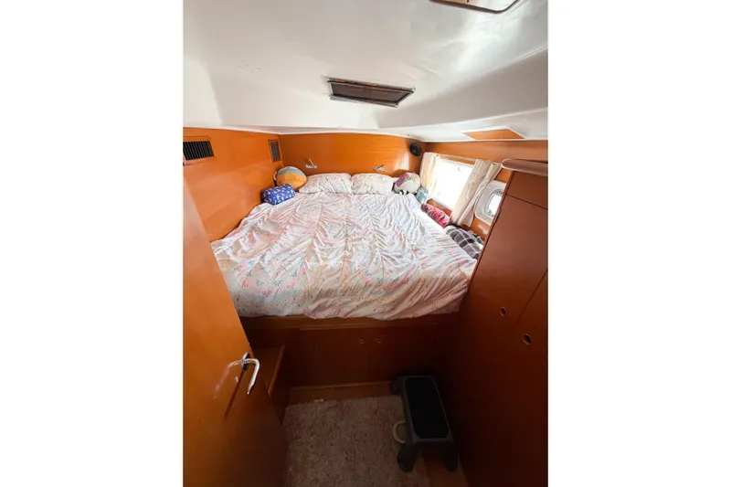 No Ka Oi Yacht Photos Pics Cozy bedroom interior of 2005 Lagoon 380 S2 catamaran with wooden finish and porthole window.