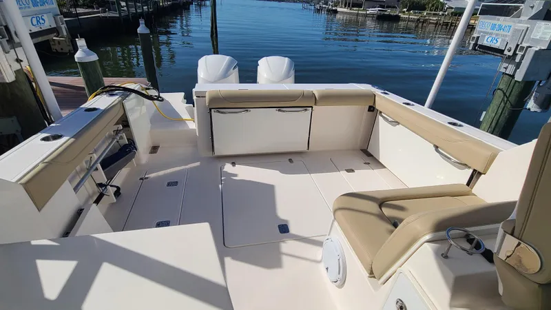  Yacht Photos Pics 2016 Pursuit DC 325 Dual Console boat interior with seating and storage, docked by calm water.
