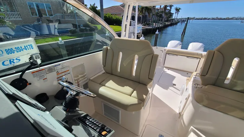  Yacht Photos Pics 2016 Pursuit DC 325 Dual Console boat interior with helm, beige seating, and waterfront view.