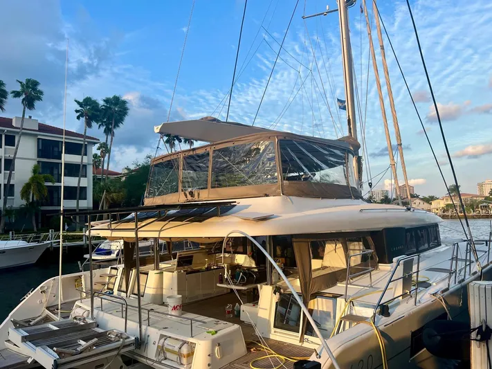  Yacht Photos Pics 2017 Lagoon 620 catamaran docked at marina, surrounded by palm trees and buildings.