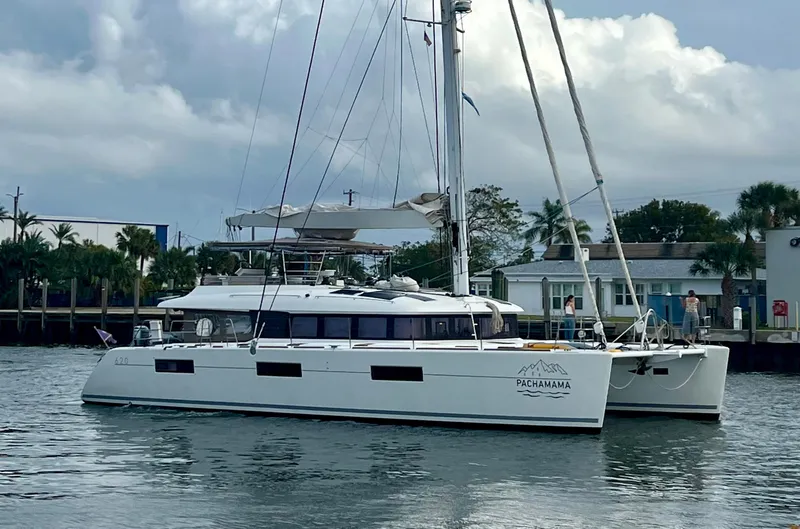  Yacht Photos Pics 2017 Lagoon 620 catamaran sailing on calm waters near a coastal town.