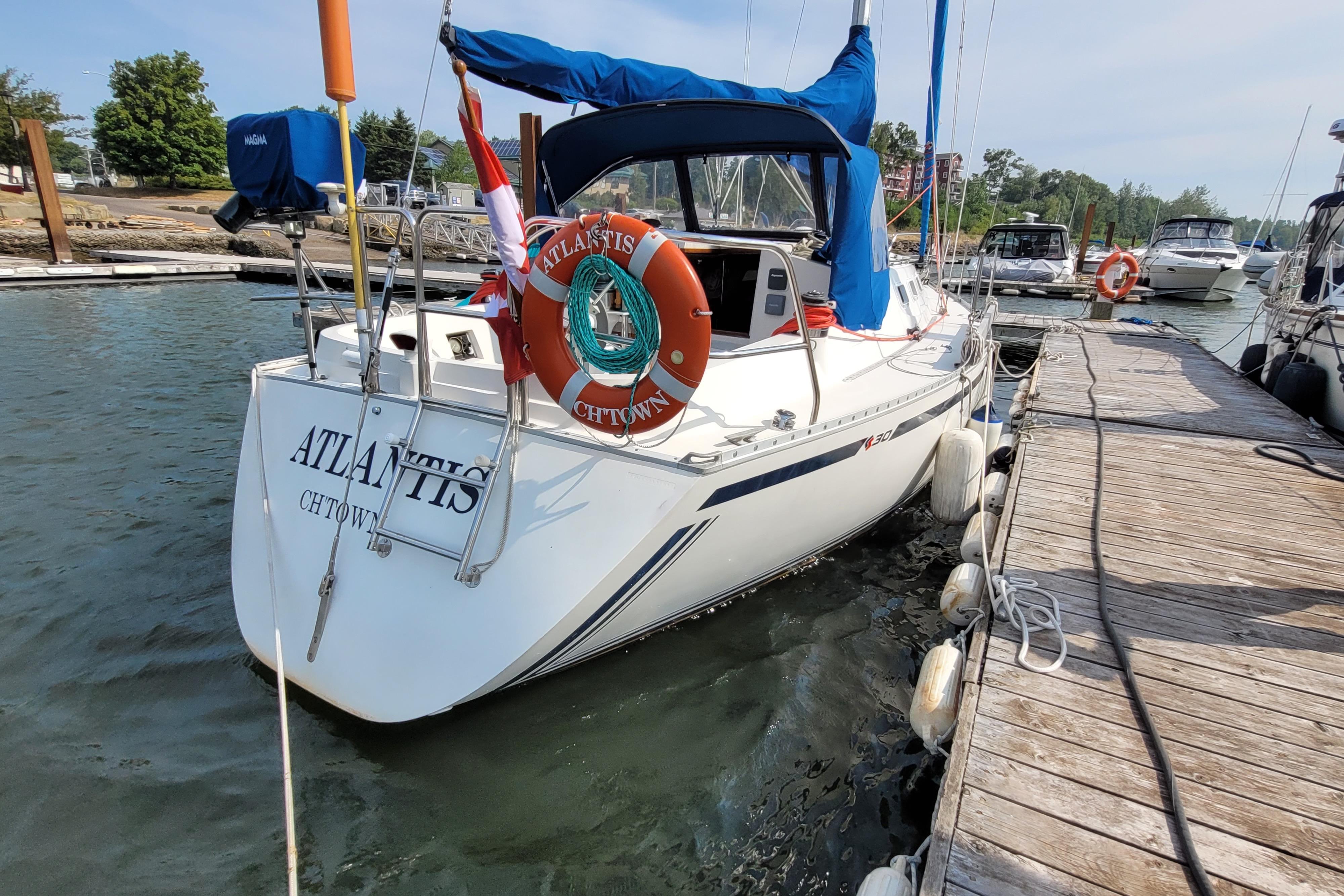 Sailboat "Atlantis" docked, CS 30 model, 1987, with lifebuoy and marina view.