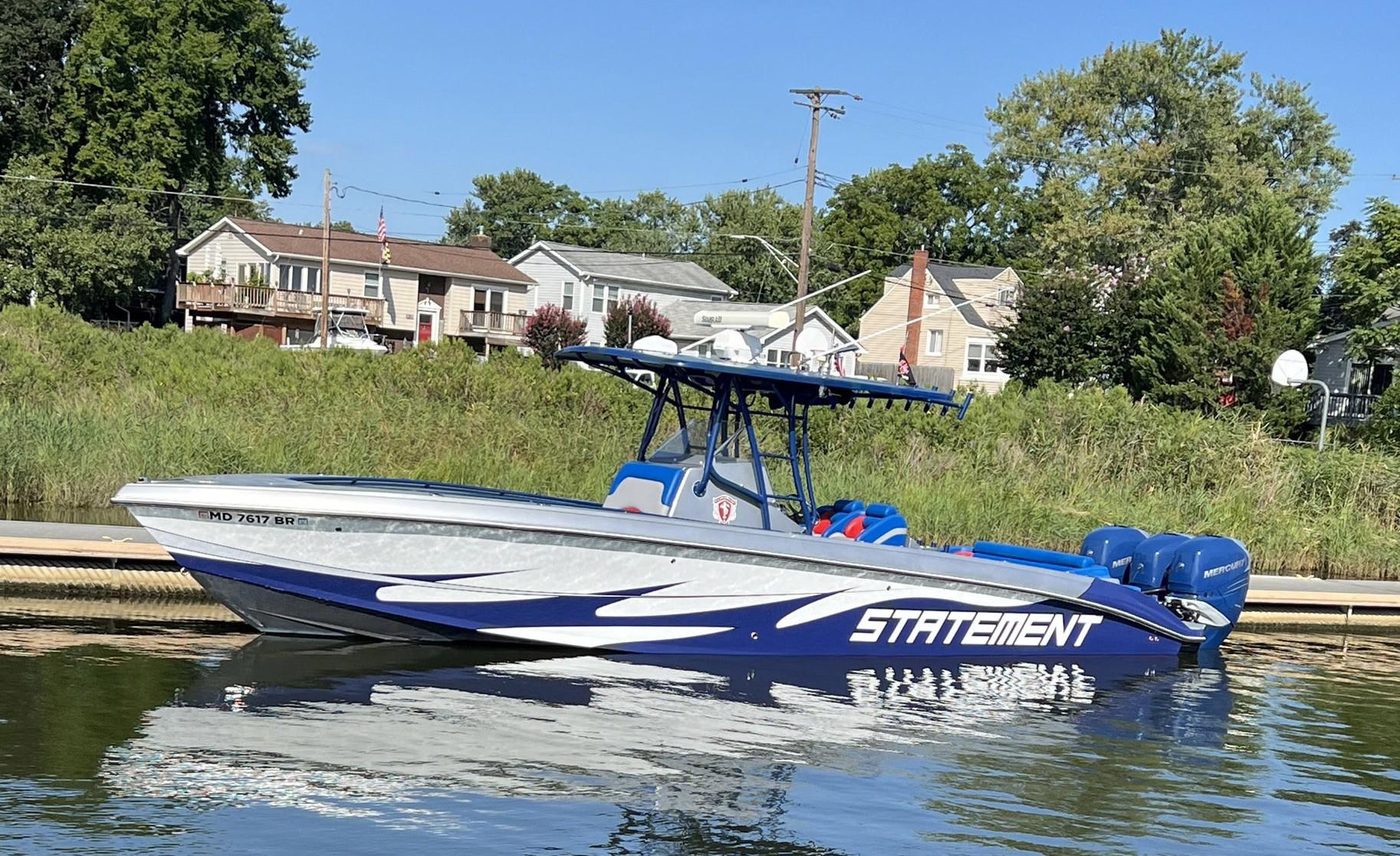 Blue and white 2011 Statement 380 Open boat docked near residential area.