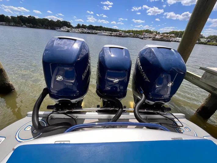  Yacht Photos Pics Triple outboard motors on a 2011 Statement 380 Open boat, docked by a scenic lake.