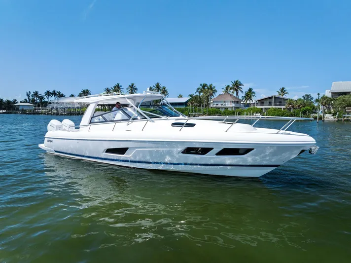 Tide Chaser Yacht Photos Pics 2022 Intrepid 438 Evolution yacht cruising on a sunny day near waterfront homes.