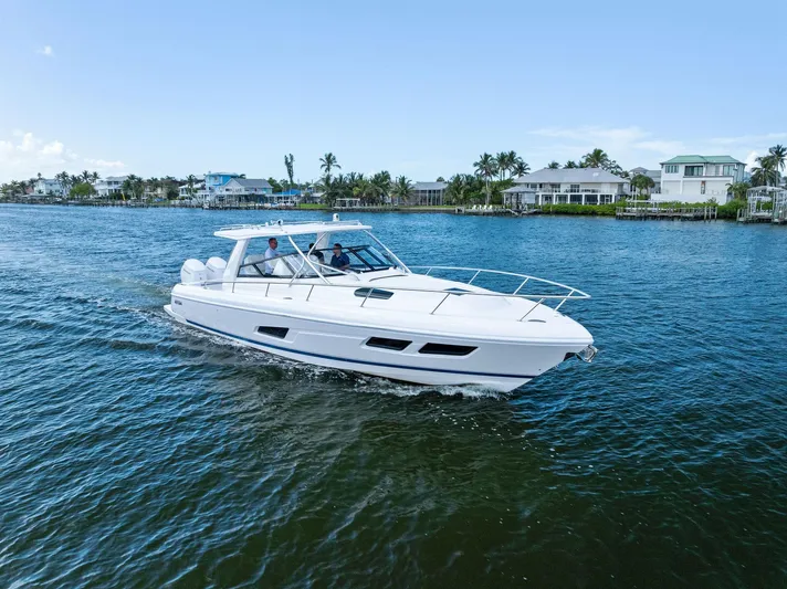Tide Chaser Yacht Photos Pics 2022 Intrepid 438 Evolution cruising on a scenic waterway with coastal homes in the background.