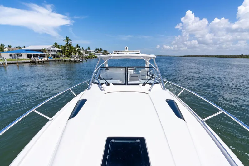 Tide Chaser Yacht Photos Pics 2022 Intrepid 438 Evolution yacht cruising on a sunny day near coastal homes.