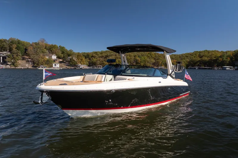  Yacht Photos Pics 2026 Chris-Craft Sportster 28 boat on a lake, surrounded by trees and clear sky.