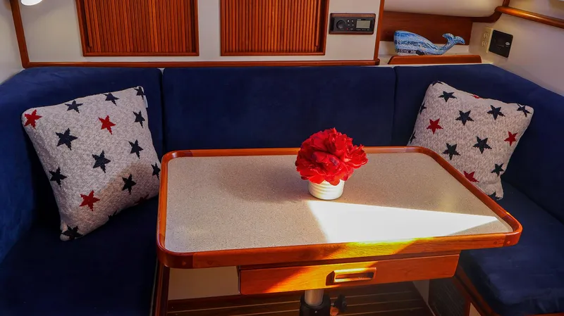 4804mm Yacht Photos Pics Cozy Fortier 33 boat interior with blue seating, star-patterned pillows, and a table centerpiece.