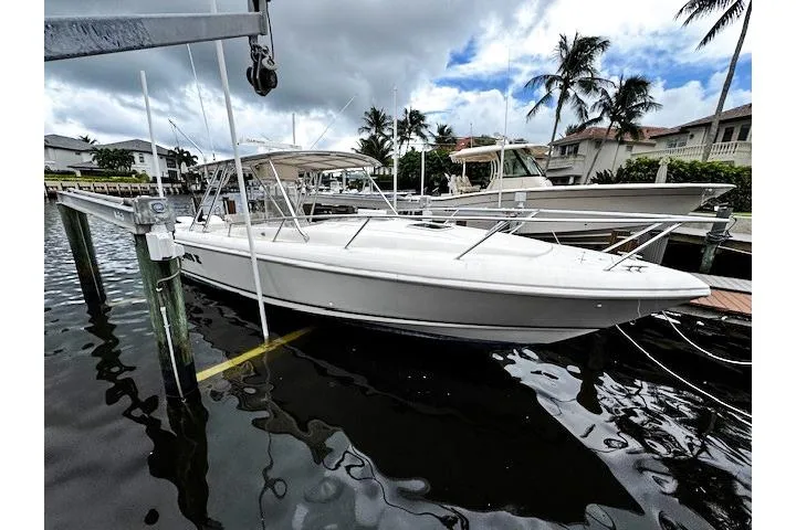  Yacht Photos Pics 1999 Intrepid 356 boat docked at marina with palm trees and cloudy sky.
