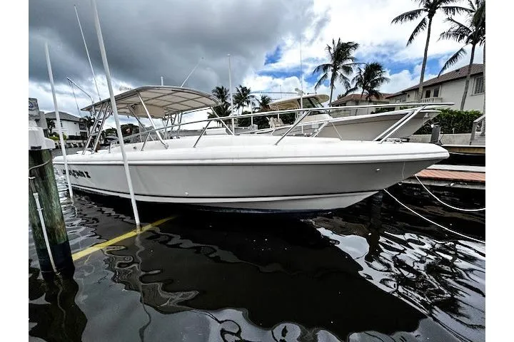  Yacht Photos Pics 1999 Intrepid 356 boat docked, with canopy, under cloudy sky and palm trees.