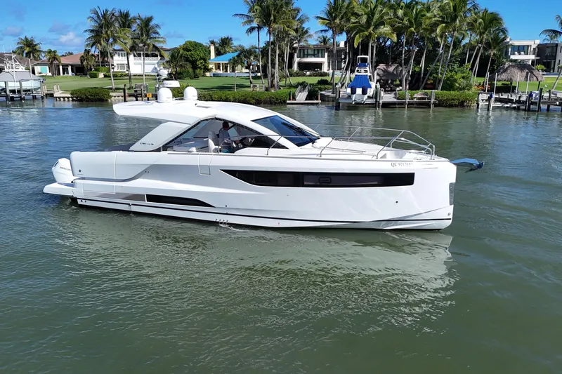  Yacht Photos Pics 2024 Jeanneau DB43 yacht cruising on a sunny day near waterfront homes.