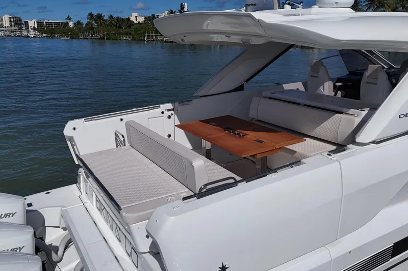  Yacht Photos Pics 2024 Jeanneau DB43 yacht with elegant seating and table on deck, docked by the water.