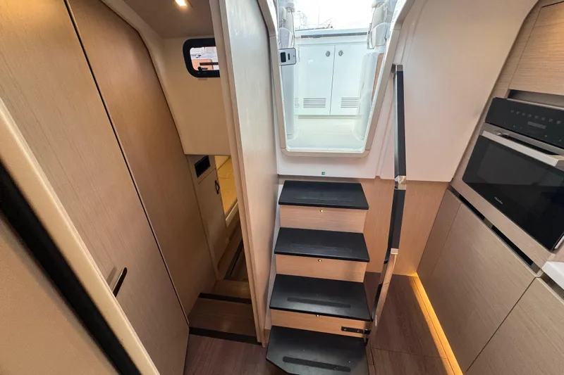  Yacht Photos Pics Interior of 2024 Jeanneau DB43 yacht, featuring modern stairs and sleek kitchen area.