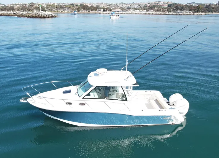 Strike Zone Yacht Photos Pics 2018 Boston Whaler 315 Conquest boat on calm blue water, equipped with fishing rods.