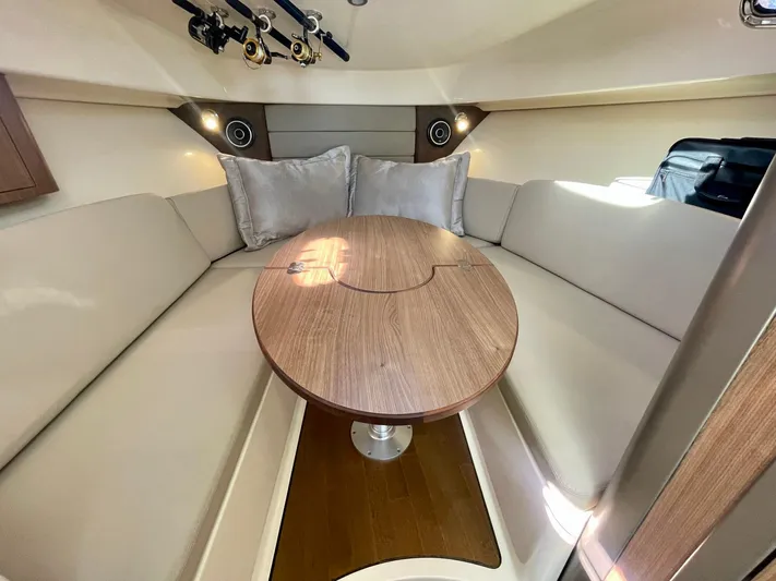 Strike Zone Yacht Photos Pics 2018 Boston Whaler 315 Conquest cabin with cozy seating and wooden table.