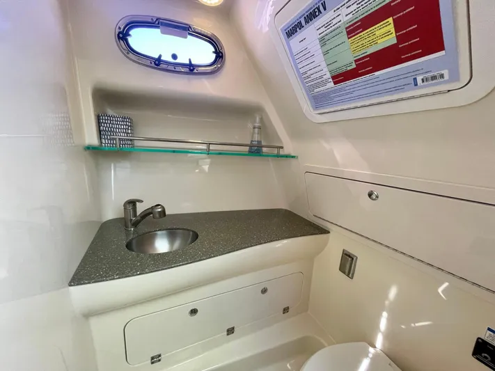Strike Zone Yacht Photos Pics 2018 Boston Whaler 315 Conquest bathroom with sink, storage, and porthole window.