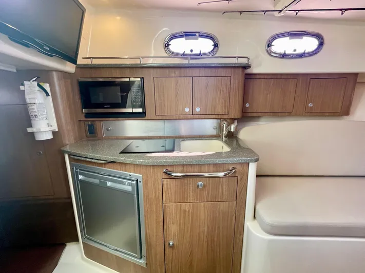 Strike Zone Yacht Photos Pics 2018 Boston Whaler 315 Conquest cabin kitchen with microwave, sink, and wooden cabinetry.