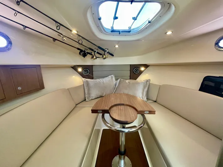 Strike Zone Yacht Photos Pics 2018 Boston Whaler 315 Conquest cabin interior with seating, table, and fishing rods.