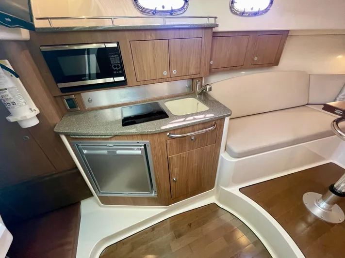 Strike Zone Yacht Photos Pics 2018 Boston Whaler 315 Conquest interior with kitchenette, featuring microwave, sink, and seating area.