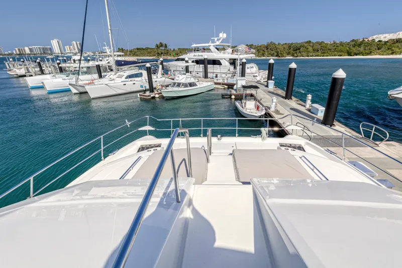  Yacht Photos Pics 2023 Aquila 54 Yacht docked at marina with clear blue water and other boats.